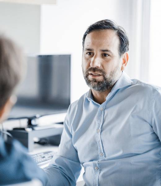 Male colleagues having meeting while sitting at their desk. Two businessmen discussing work at workplace.